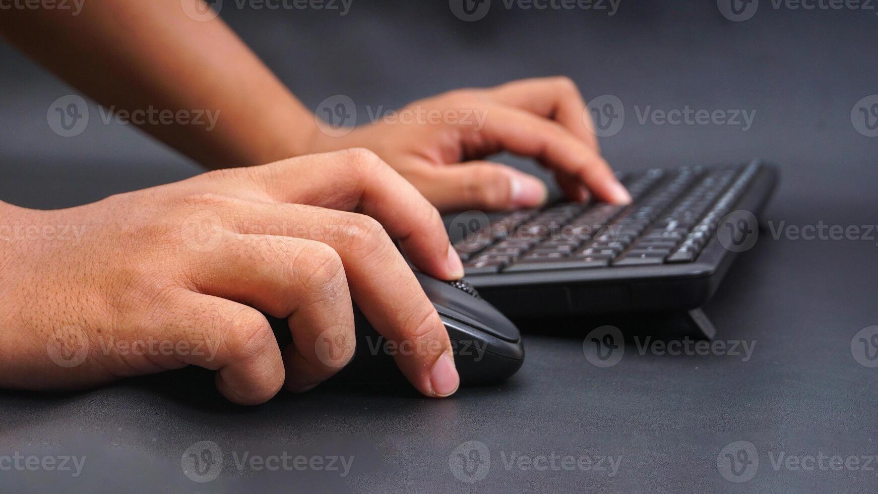 Man hand typing on computer keyboard and holding computer mouse isolated on black background photo