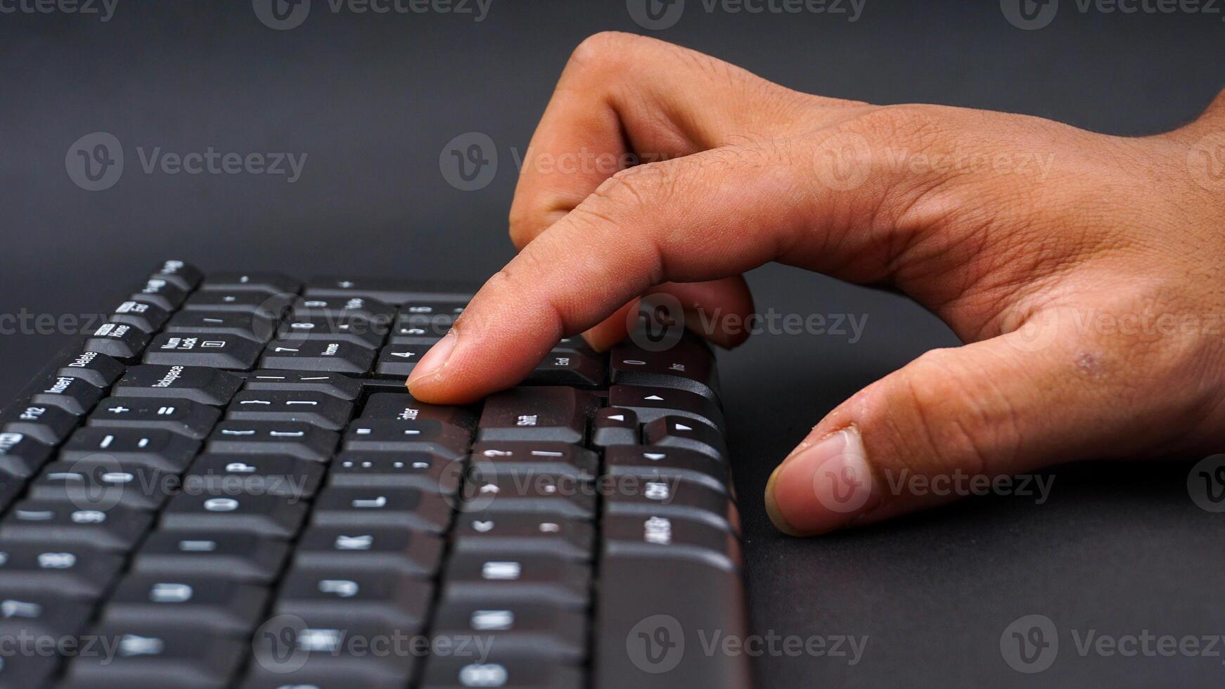 Fingers typing on a computer keyboard isolated on black background photo