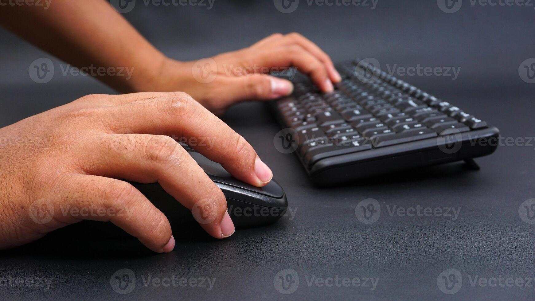 Man hand holding computer mouse and typing on keyboard isolated on black background photo