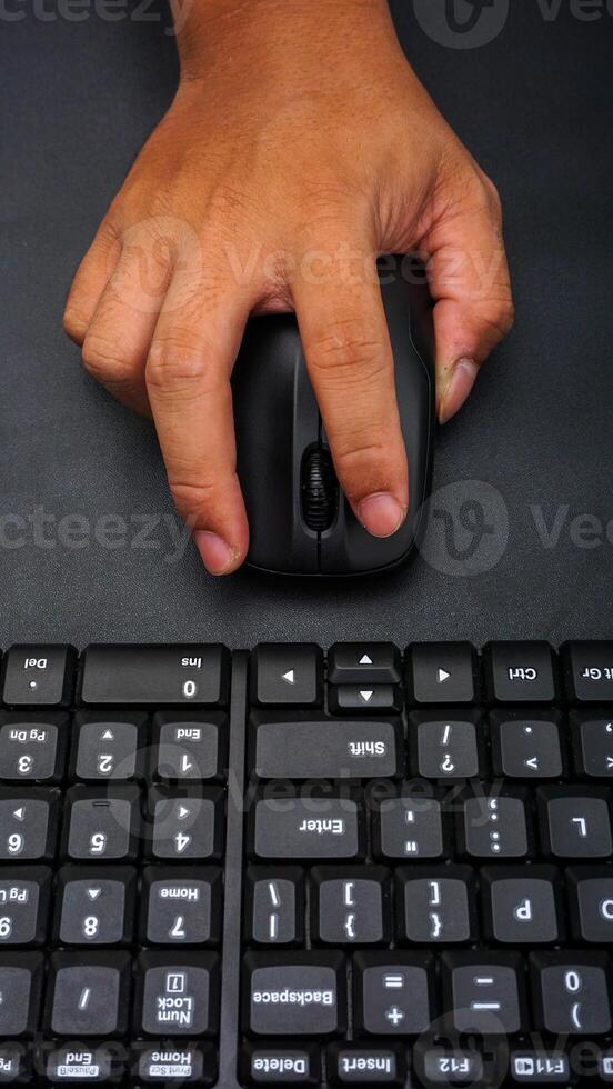 Computer keyboard with man hand holding computer mouse isolated on black background photo