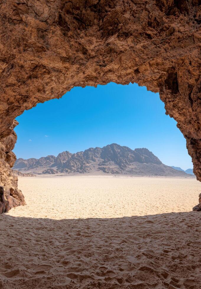 A cave opening overlooking a desert landscape with mountains in the distance photo