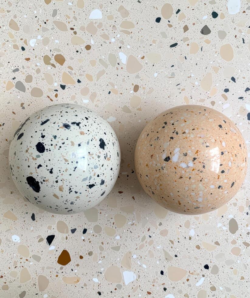 Two decorative terrazzo spheres on a terrazzo surface photo