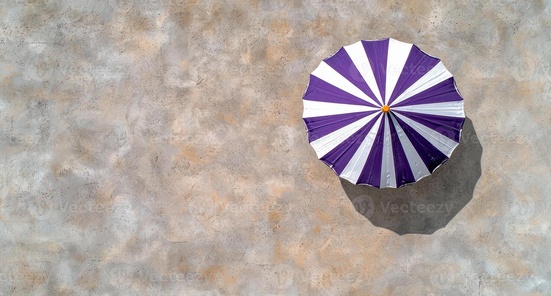 Aerial view of a purple and white striped beach umbrella on a textured surface photo