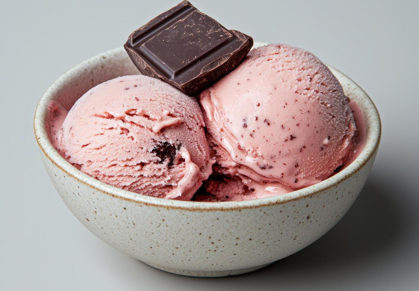 A bowl of strawberry ice cream with a square of dark chocolate photo