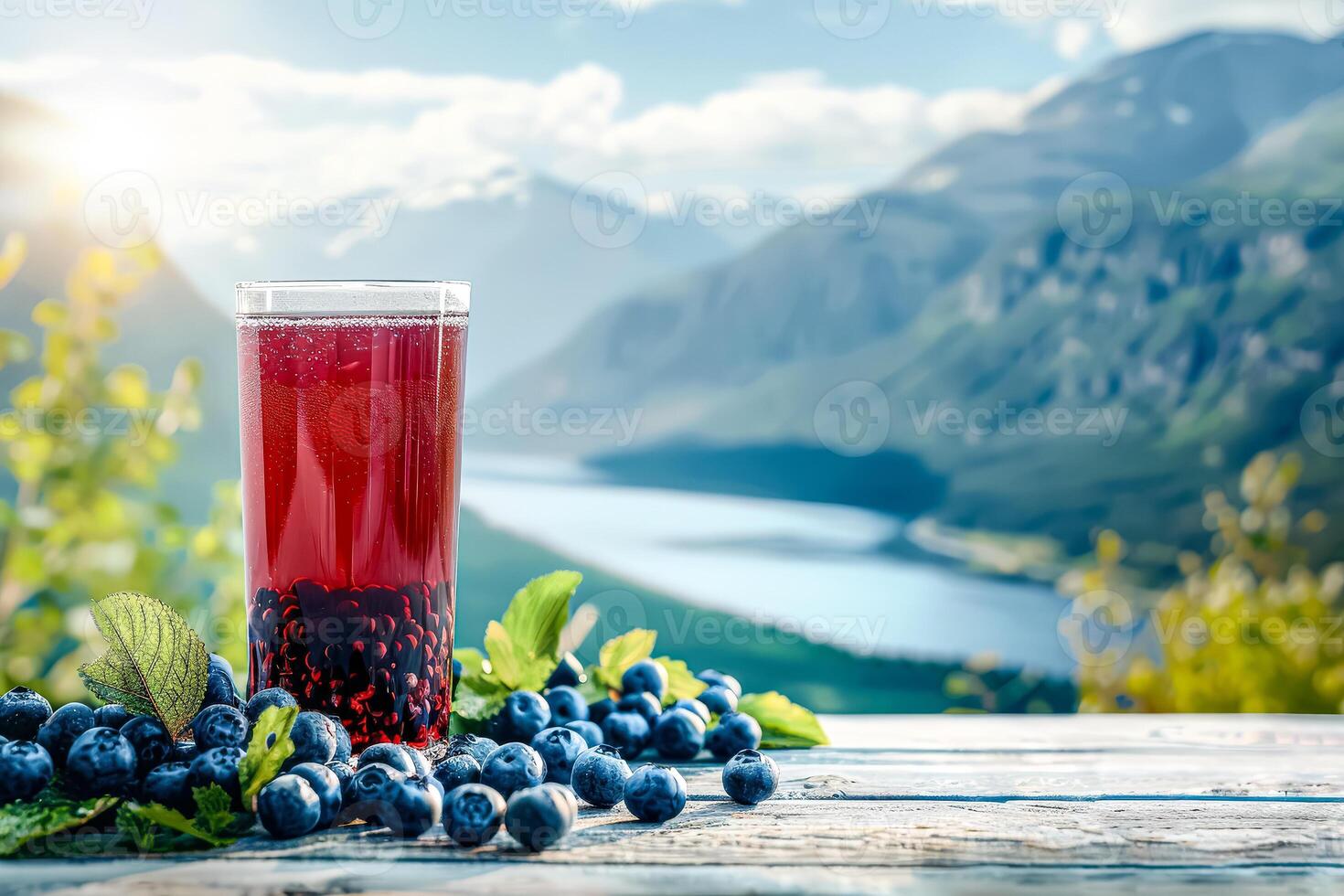 Glass of red juice is on a table with a bunch of blueberries photo
