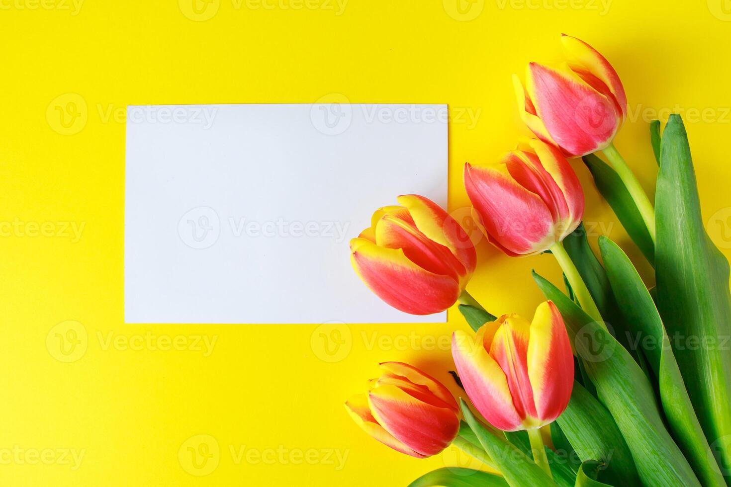 Bouquet of pink tulips and greeting card on a yellow background. Invitation to holiday. photo
