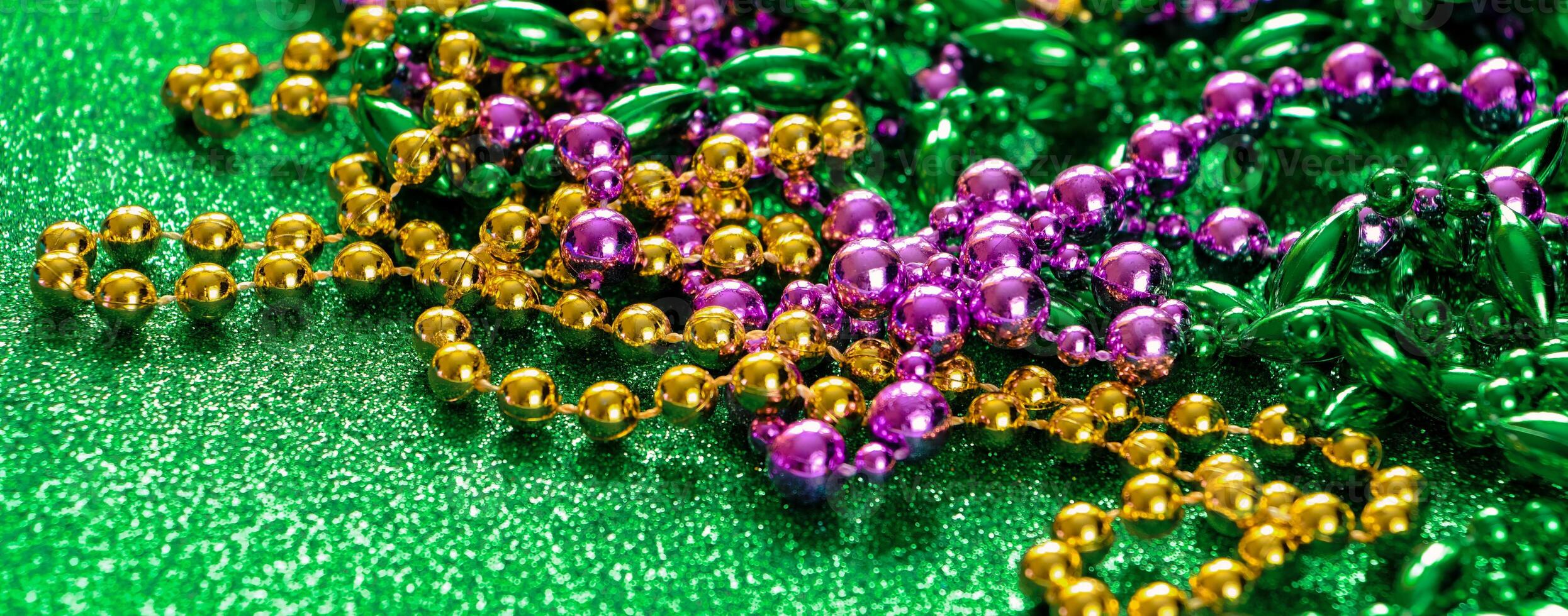 Mardi Gras concept. Multi-colored beads on green shiny background. Fat Tuesday symbol. photo