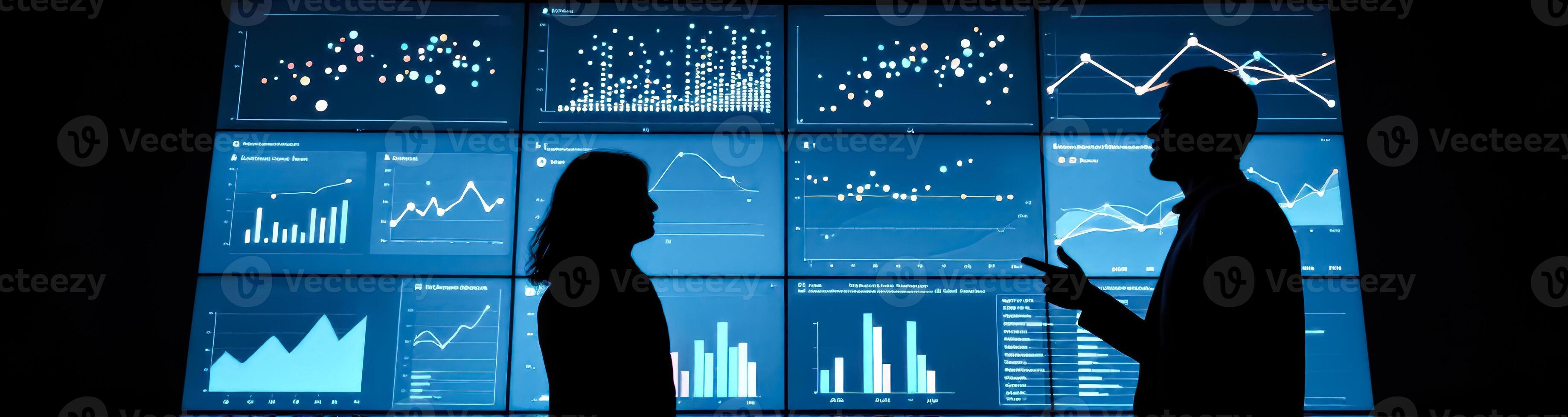 two silhouetted businesspeople analyzing data on multiple screens photo