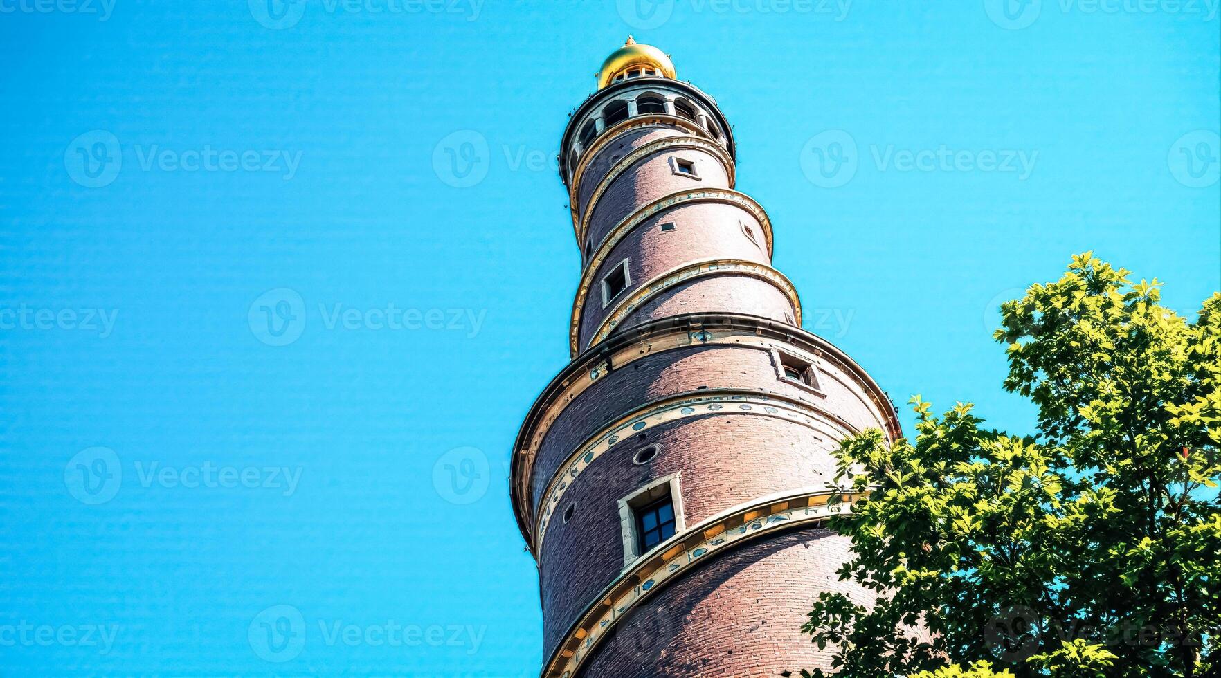 majestic spiral brick tower with gold accents stands tall against a vibrant blue summer sky photo