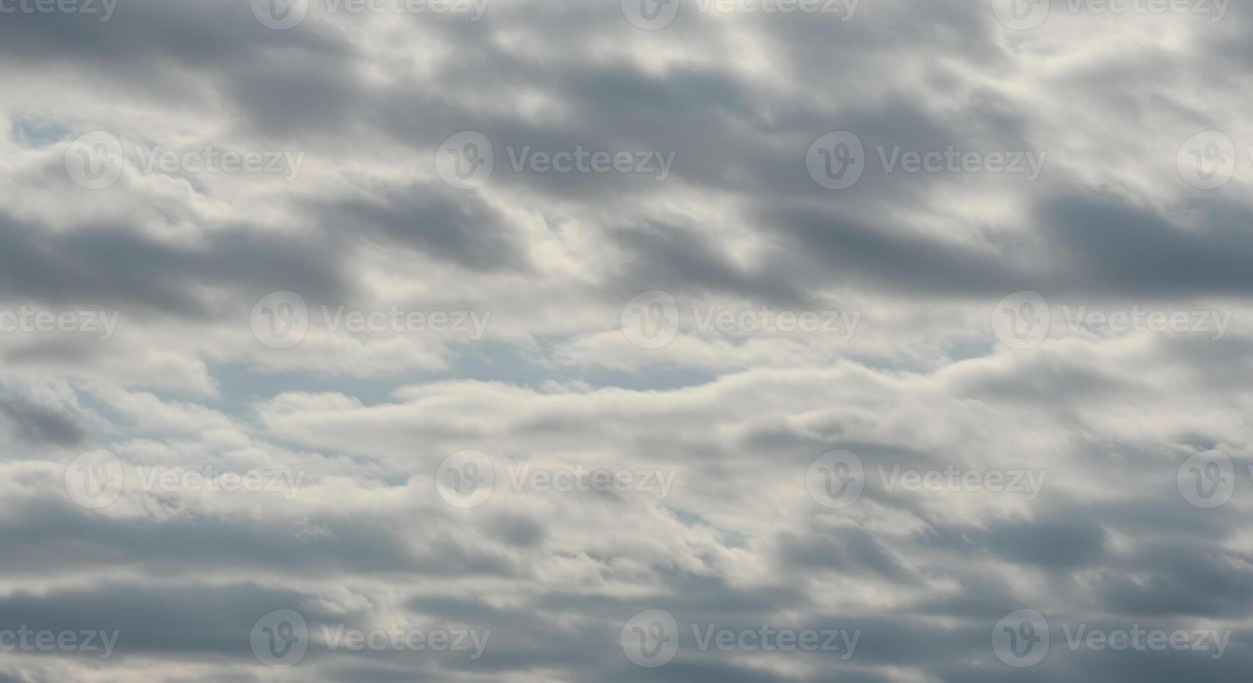 Layers of soft gray and white clouds drift serenely in the expansive sky above. photo