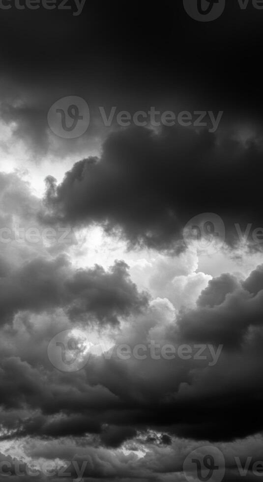 Dramatic dark clouds fill the sky, creating a moody monochrome cloudscape with soft light. photo
