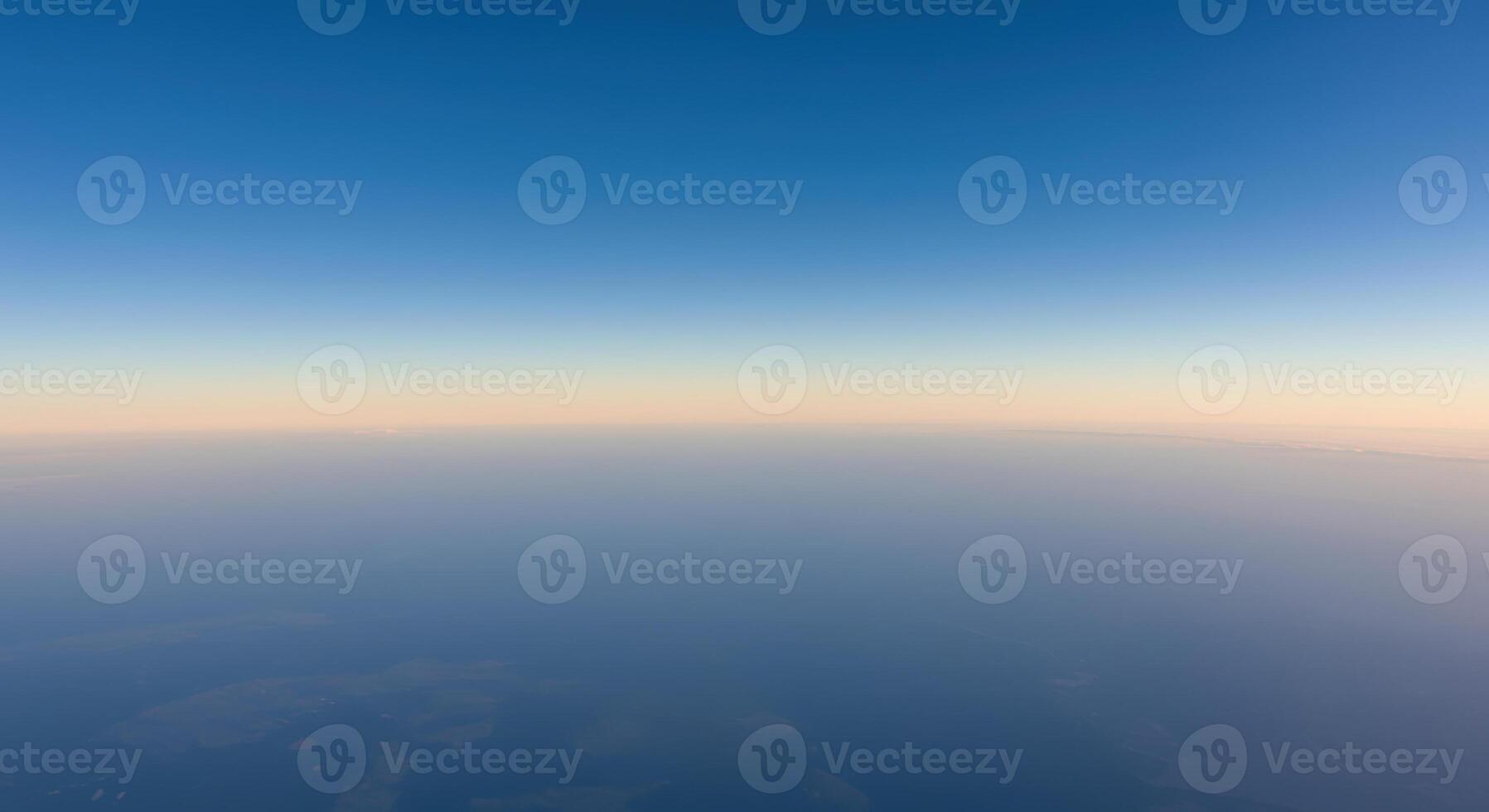 Aerial view of a serene horizon showcasing a gradient of blue sky meeting a foggy earth. photo