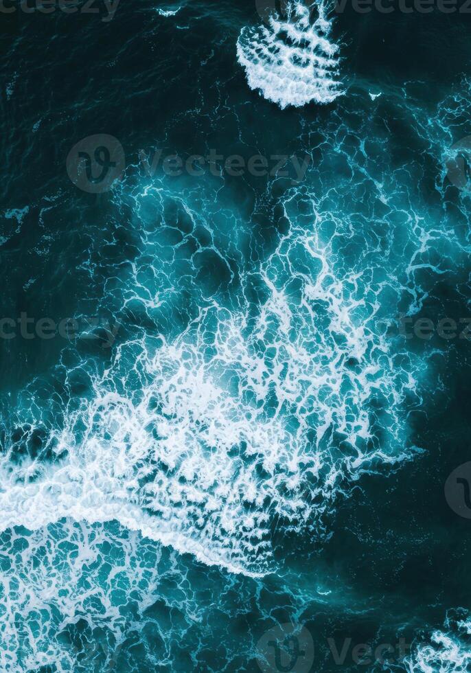 Overhead view of deep turquoise ocean water and foamy waves, creating abstract patterns. photo
