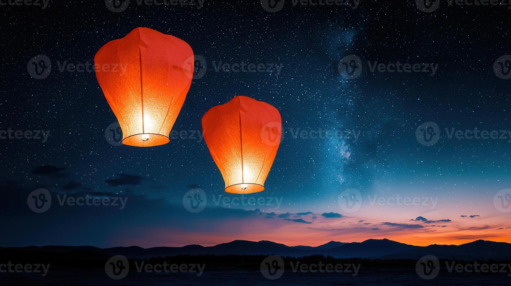 Two Illuminated Sky Lanterns Ascending Against a Starry Night Sky over Silhouetted Mountains photo
