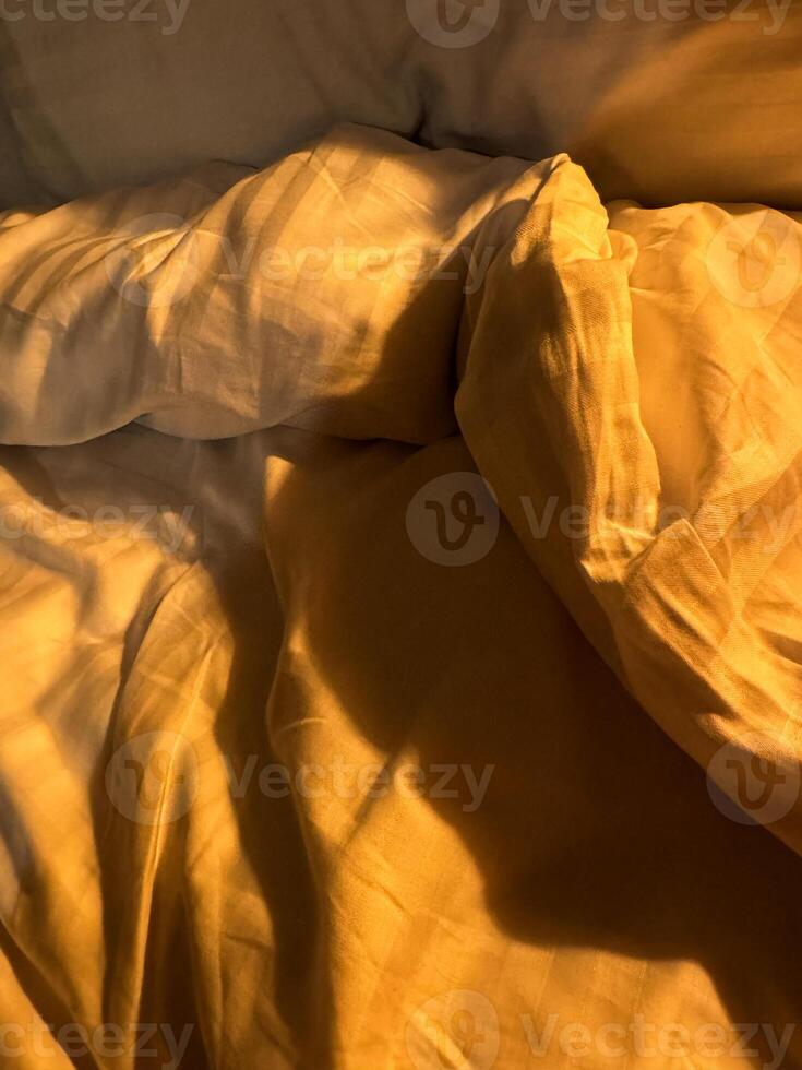 Soft golden light illuminates cozy bedding in a tranquil bedroom setting photo