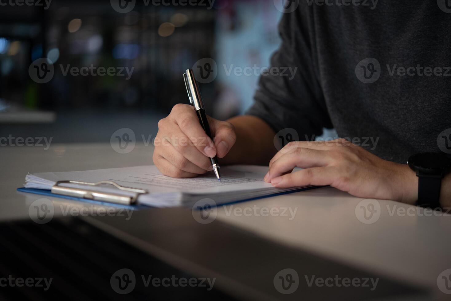 A man writing on a notepad with a pen photo