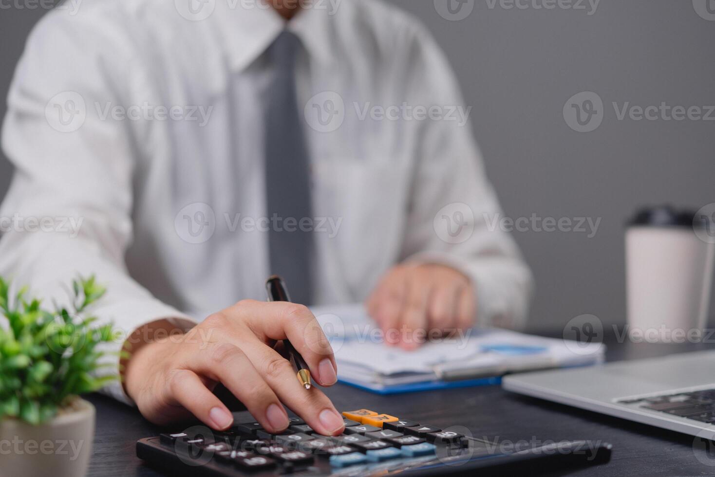 A man in a white shirt is using a calculator photo