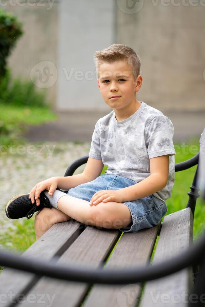 A Thoughtful Boy Sitting on a Bench, Gazing Calmly into the Camera photo