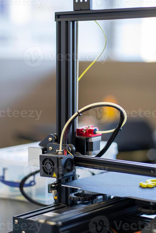 View of a working 3D printer mechanism printing a plastic part photo