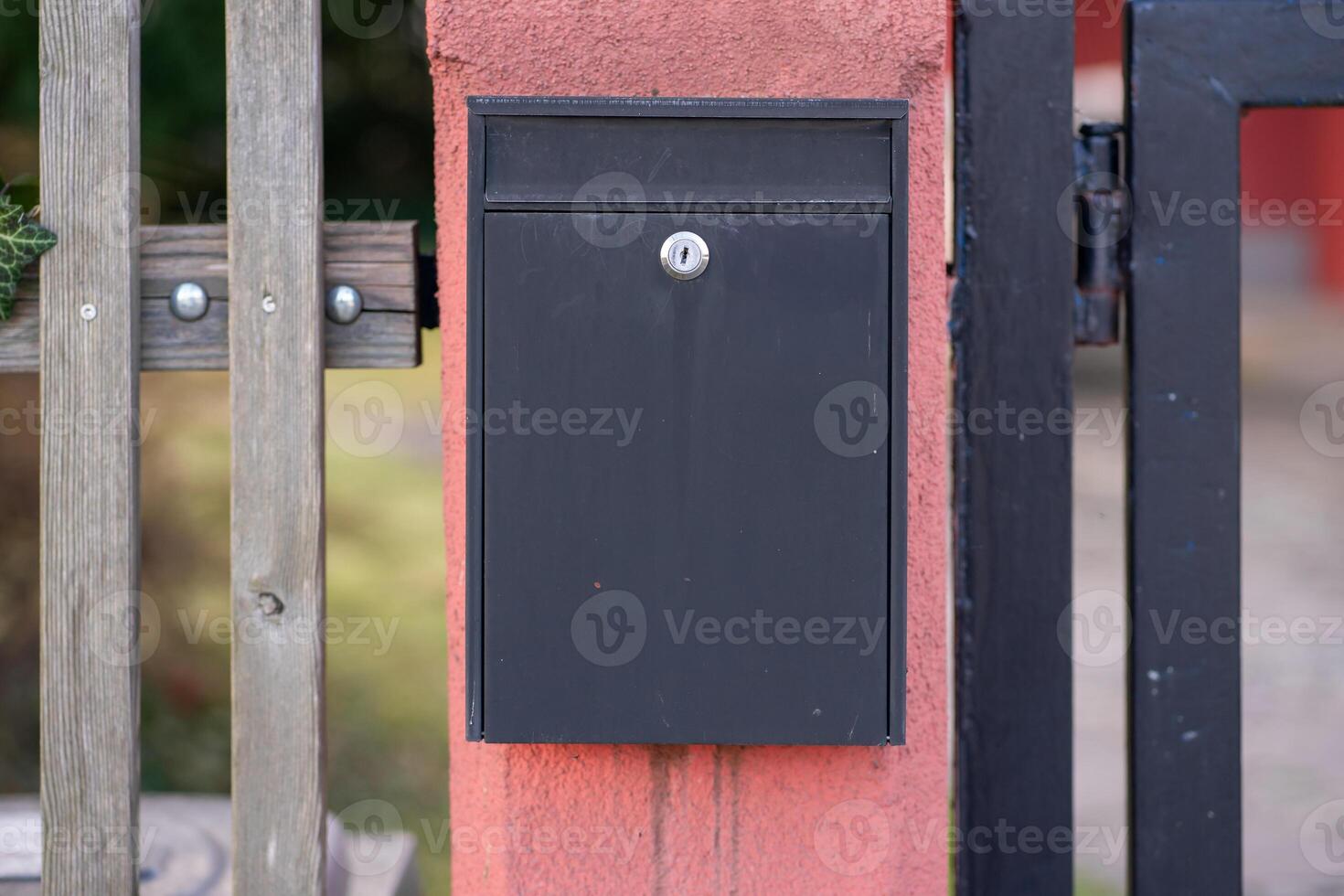 View of a gray mailbox for newspapers and letters hanging on a fence wall photo