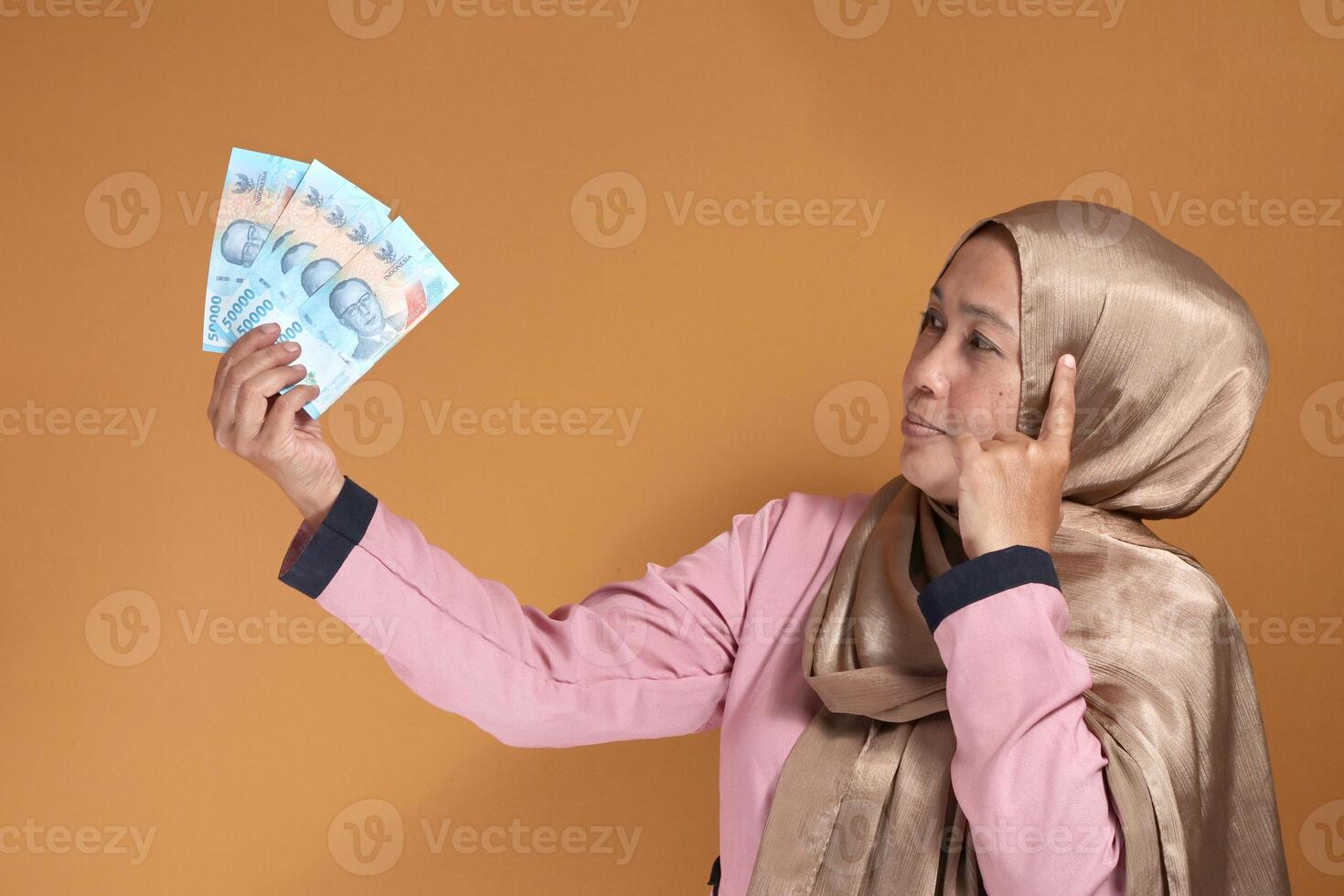 Confident woman holding Indonesian Rupiah money, showing financial success and decision making photo