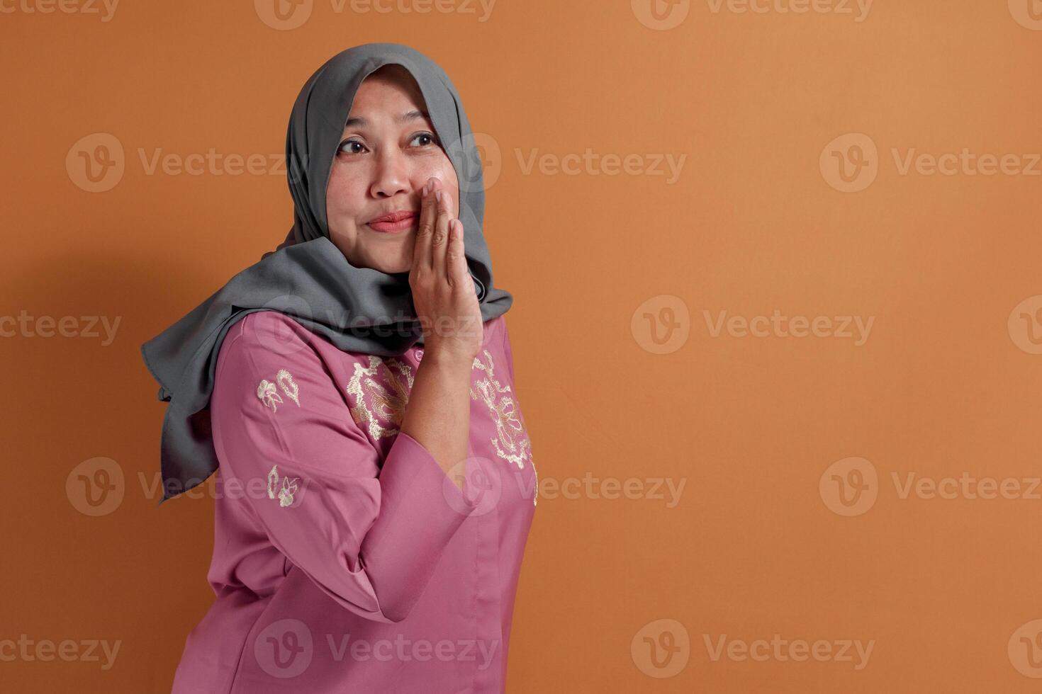 Surprised muslim woman reacting with curious face and hand on cheek photo