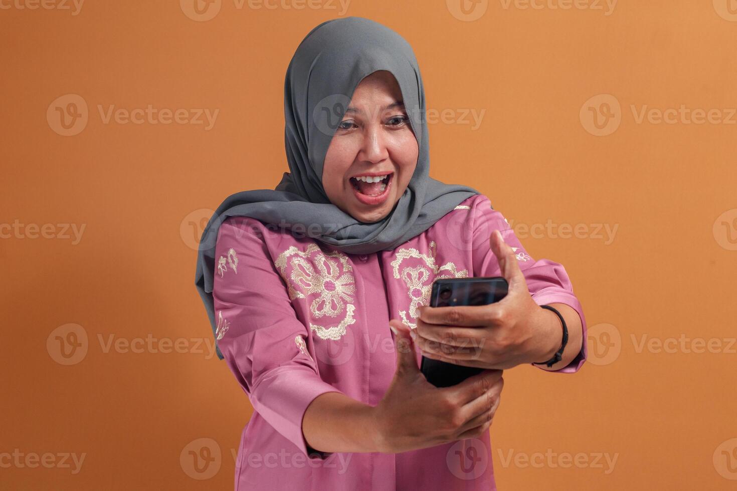 Excited Muslim woman enjoying call using smartphone at home photo