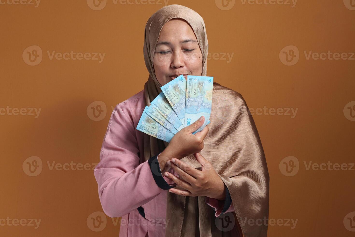 Happy Woman Holding Indonesian Rupiah Money with Eyes Closed photo