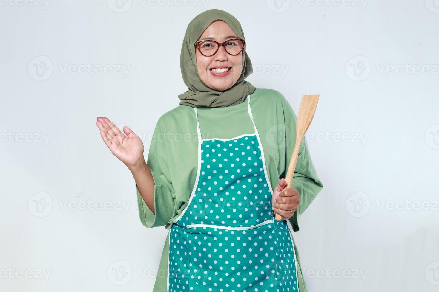 Home chef smiling while holding a wooden spoon, ready to cook delicious meals photo