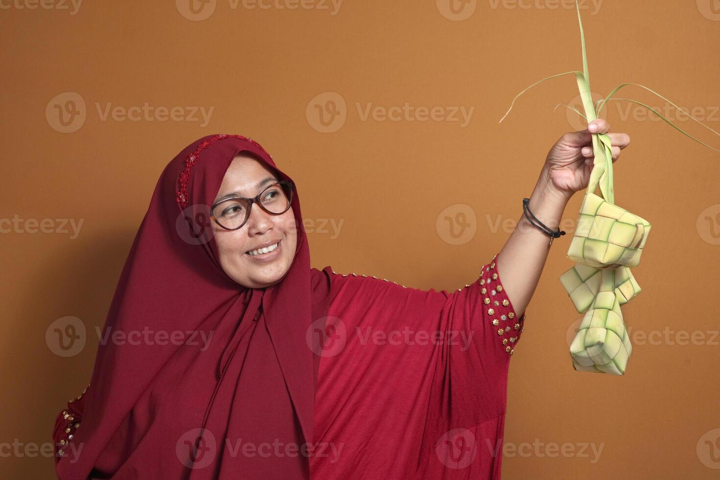 Muslim woman joyfully holding ketupat, a traditional dish for Eid celebration photo