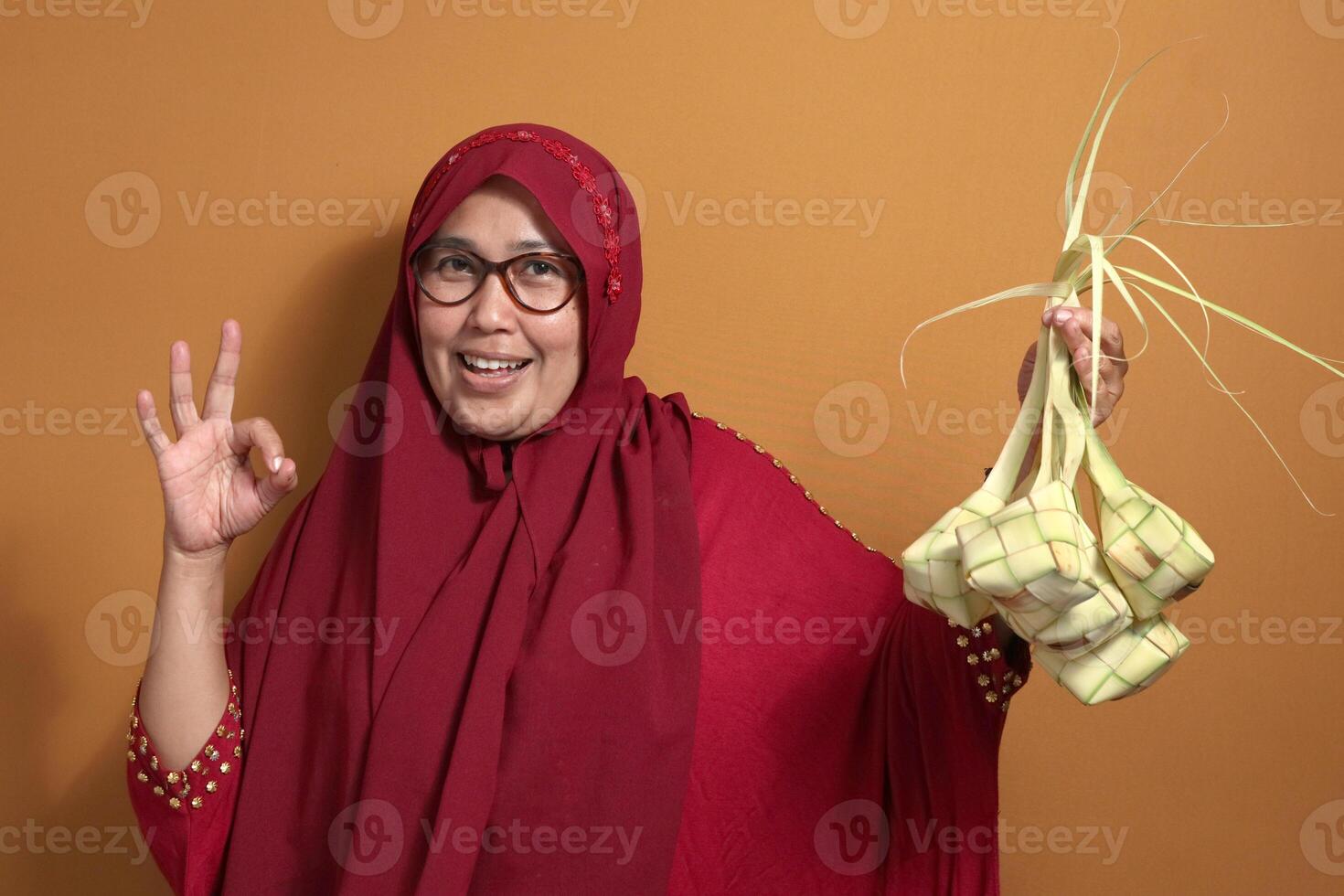 Happy Muslim woman holding ketupat for Eid celebration, expressing joy and tradition photo