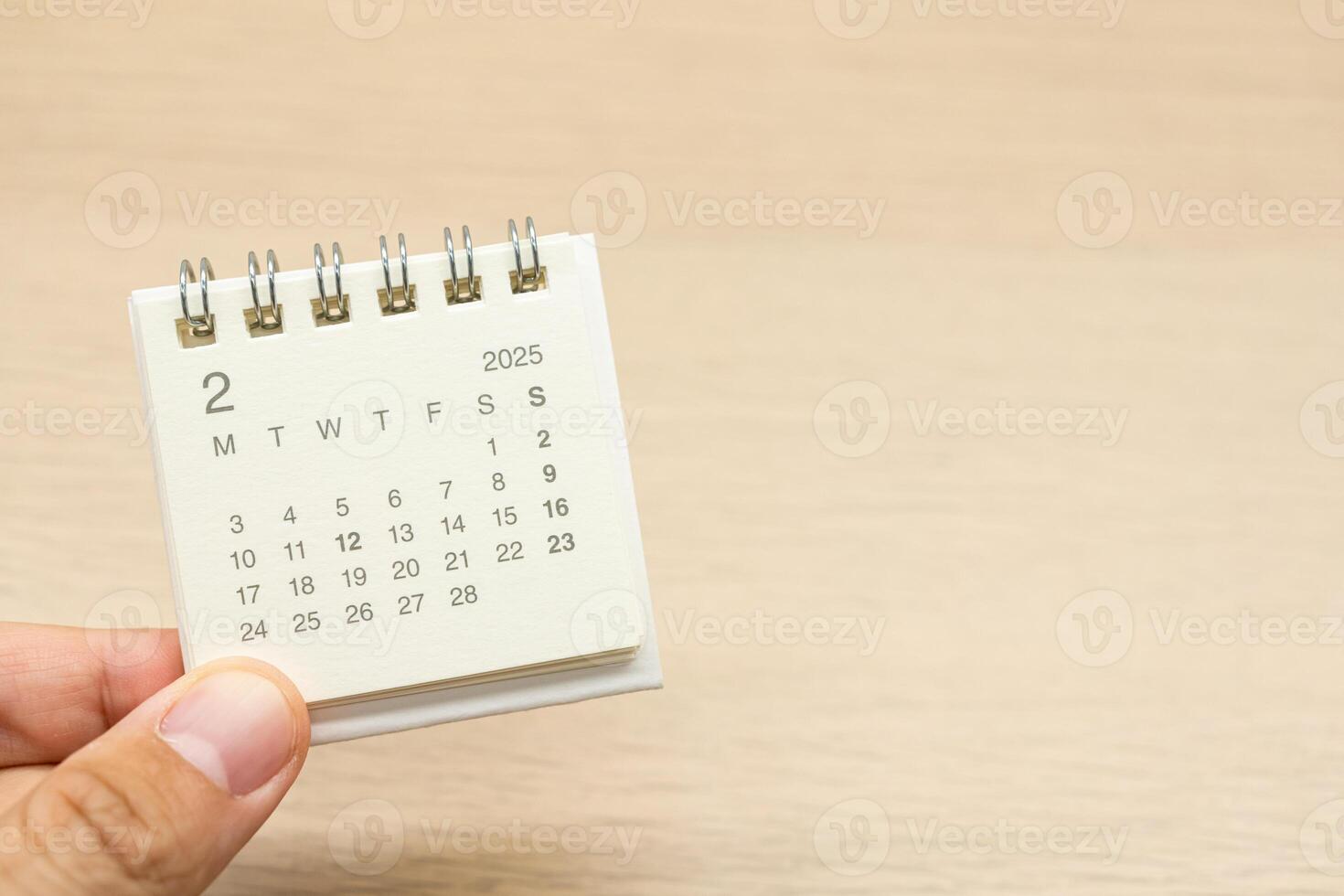 Hand holding mini Calendar for FEBRUARY 2025 background. Calendar concept with 2025 FEB calendar on wooden background. Copy Space for text. photo