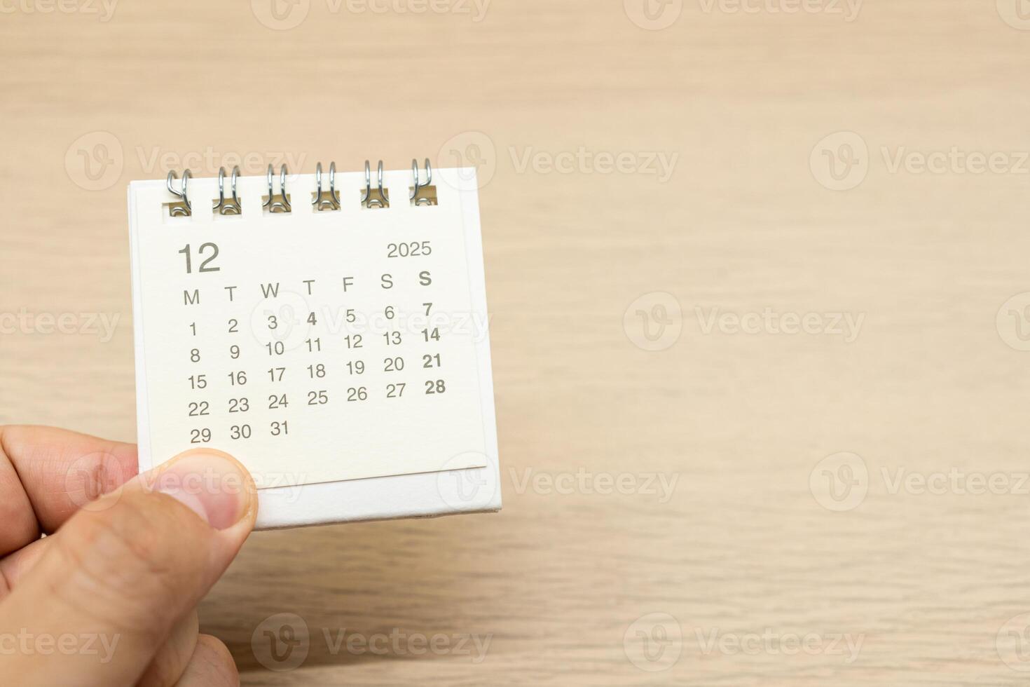 Hand holding mini Calendar for DECEMBER 2025 background. Calendar concept with 2025 DEC calendar on wooden background. Copy Space for text. photo