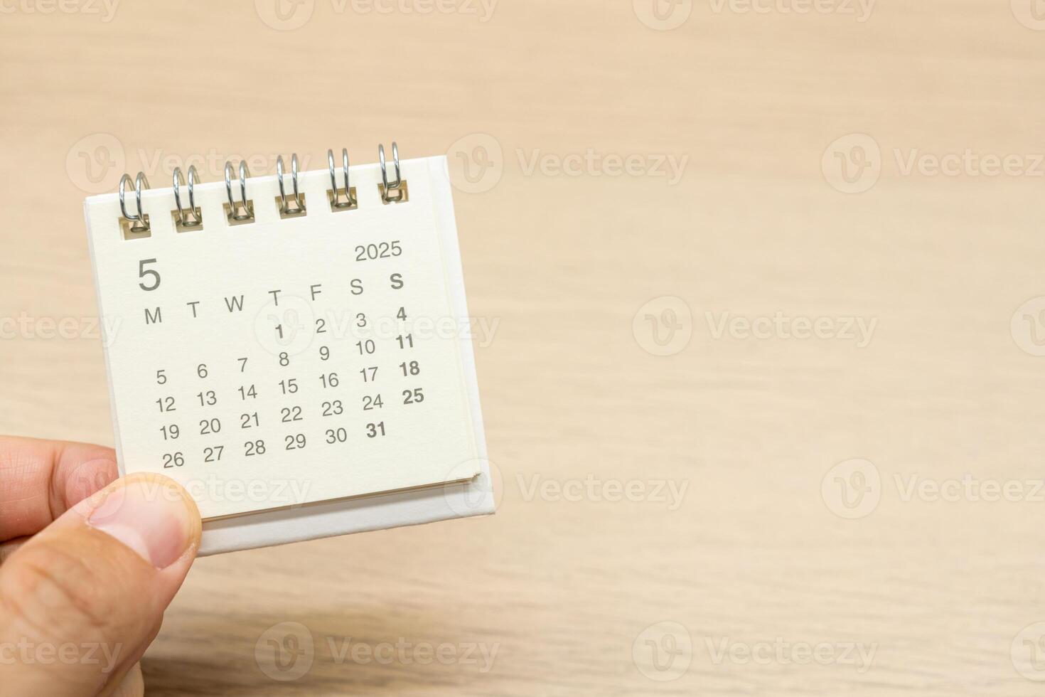 Hand holding mini Calendar for MAY 2025 background. Calendar concept with 2025 MAY calendar on wooden background. Copy Space for text. photo