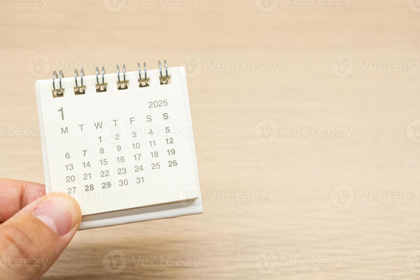Hand holding mini Calendar for JANUARY 2025 background. Calendar concept with 2025 JAN calendar on wooden background. Copy Space for text. photo