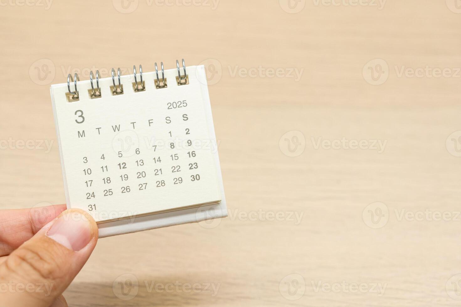 Hand holding mini Calendar for MARCH 2025 background. Calendar concept with 2025 MAR calendar on wooden background. Copy Space for text. photo