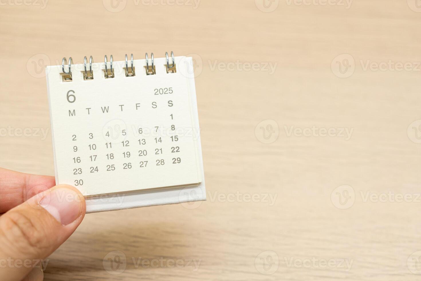 Hand holding mini Calendar for JUNE 2025 background. Calendar concept with 2025 JUN calendar on wooden background. Copy Space for text. photo