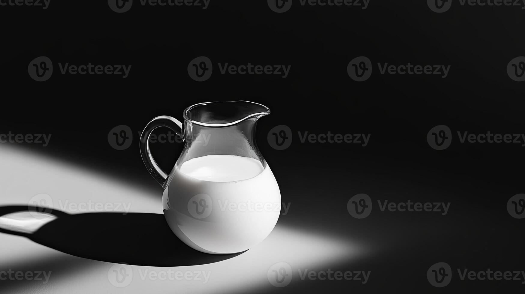 Simple and clean glass pitcher filled with milk, set on a dark background for a minimalist and modern visual concept. photo