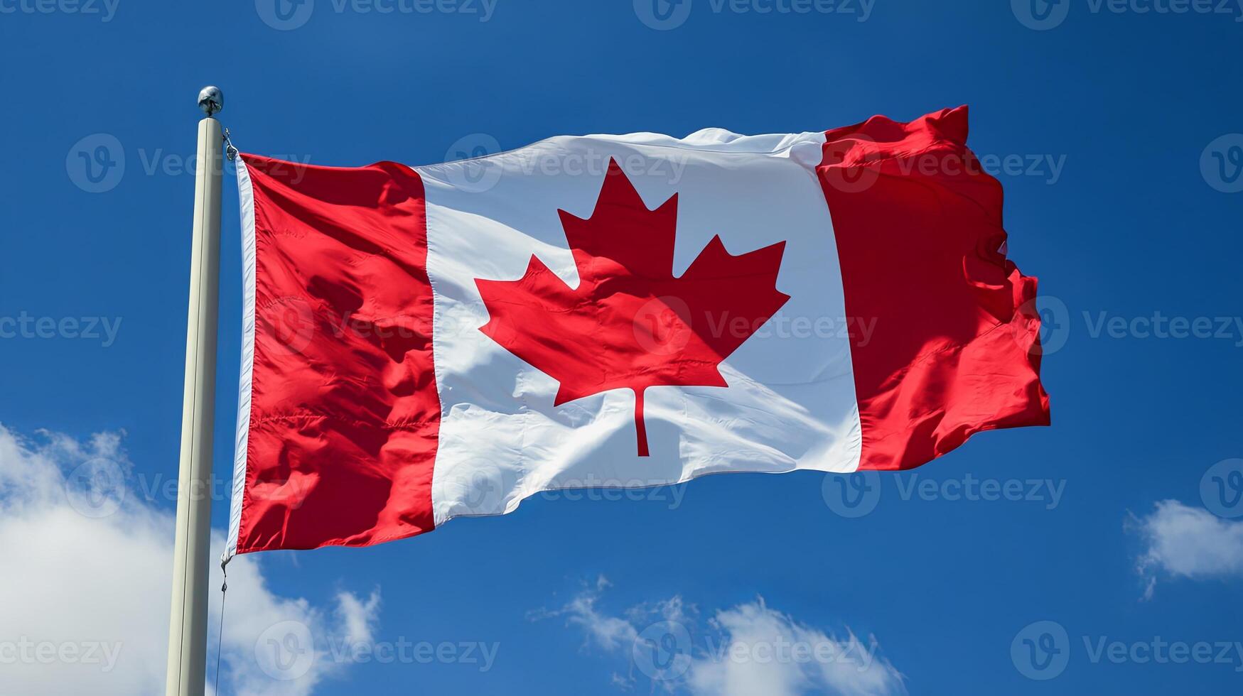 Canadian flag fully unfurled and waving in the wind under a blue sky, representing strength, pride, and unity. photo