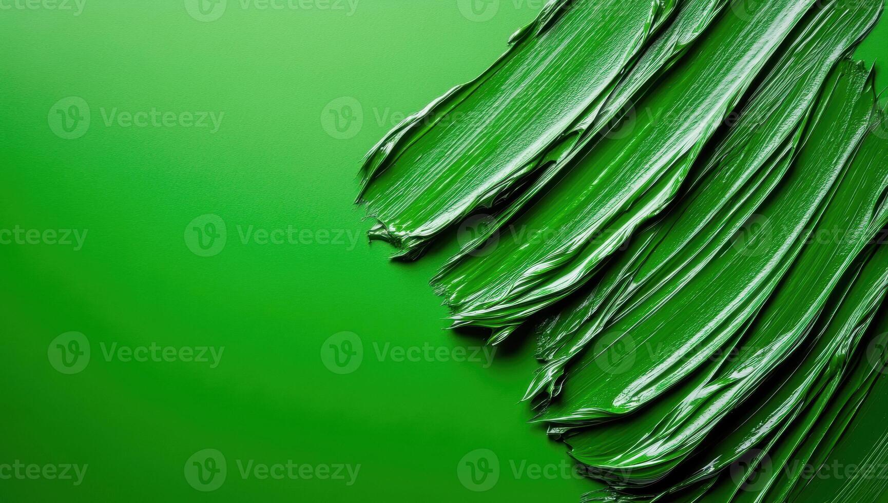 Thick glossy green paint is creating dynamic diagonal lines on matching green background with copy space photo
