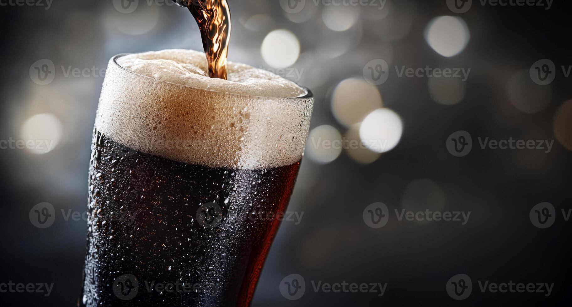 beer being poured into a glass, forming a frothy head and condensation on a blurred backdrop photo