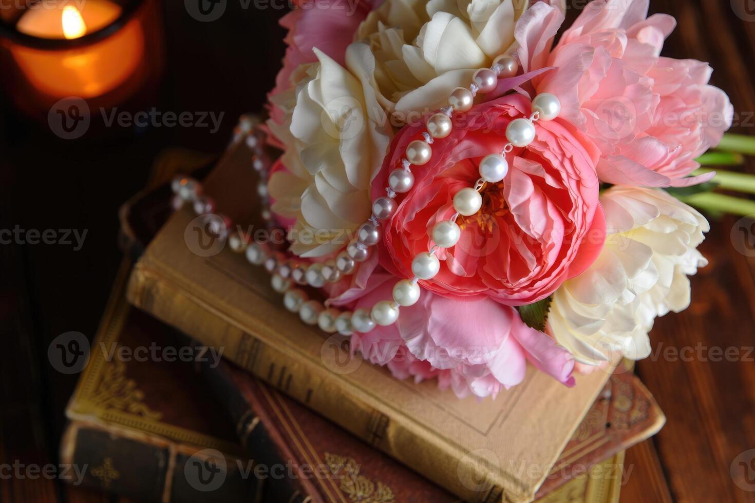 Elegant floral arrangement with pearls and vintage books at cozy evening setting photo