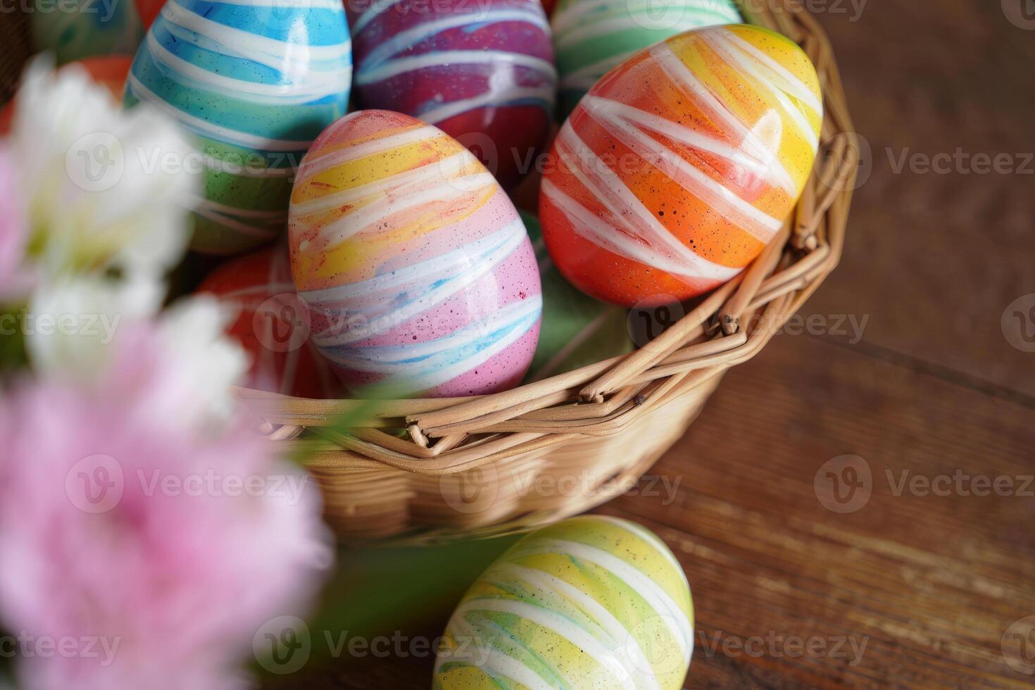 An Easter basket overflowing with brightly colored eggs and soft, blurred flowers. photo