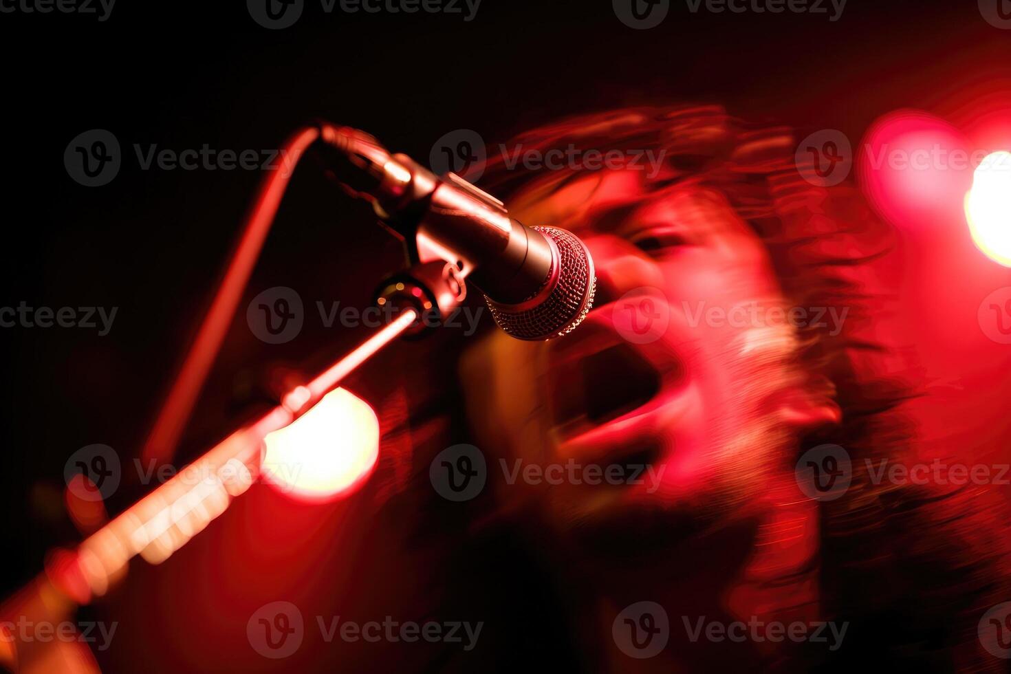 Musician performs passionately under vibrant red lights during an energetic concert photo