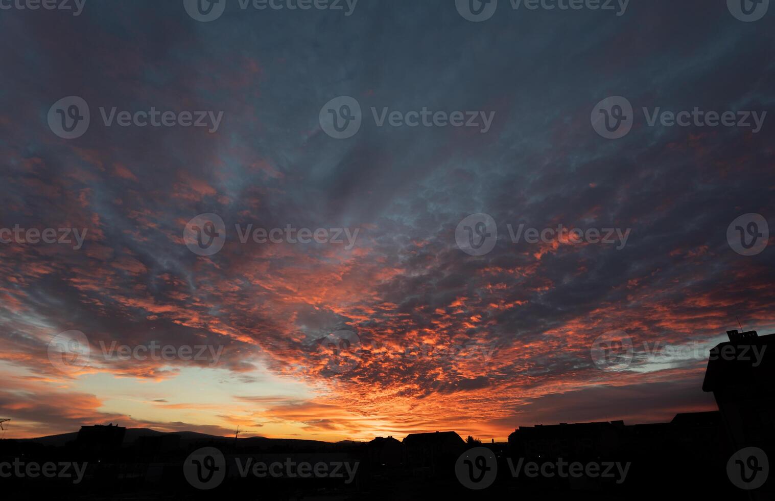 The fiery sunset illuminates the sky, casting a warm glow over the urban landscape below. photo