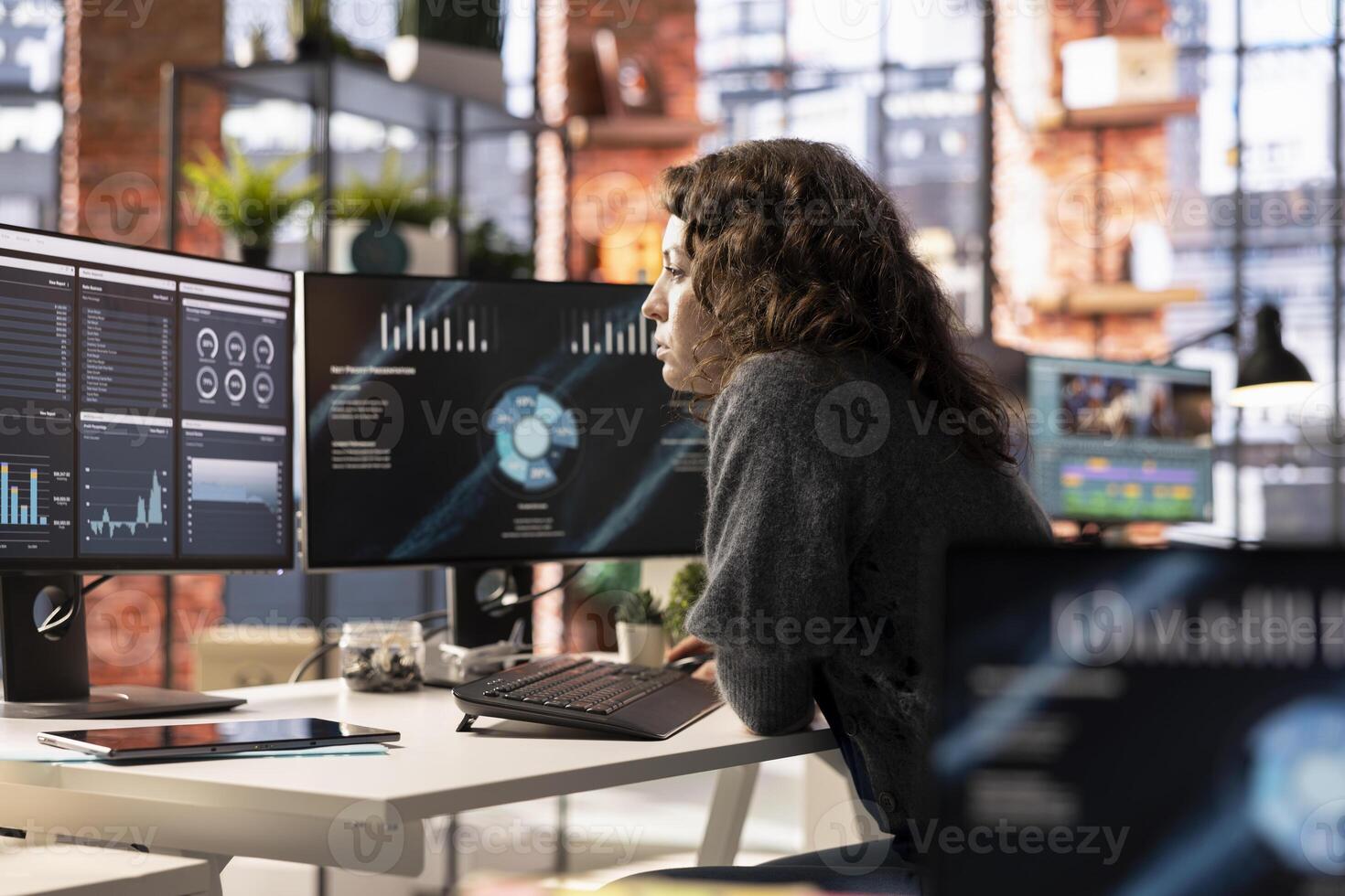 Young woman watching business conference infographics on computer screen, looking over statistics on online portfolio. Analyst in apartment looking at business presentation dashboard. photo