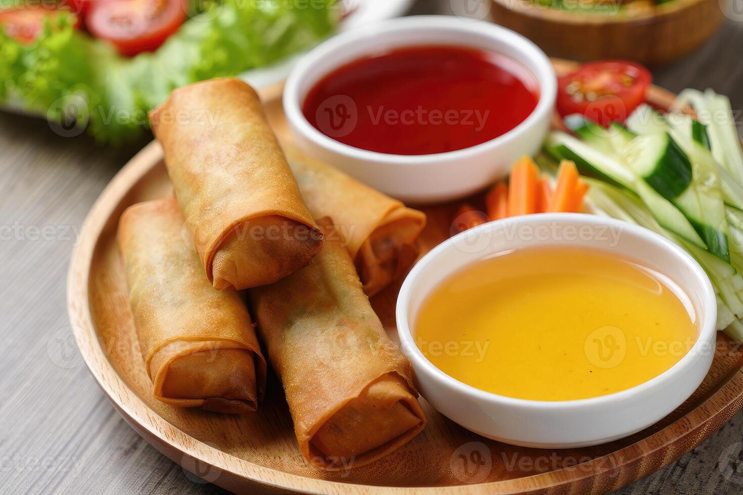 Delicious spring rolls served with dipping sauces and fresh vegetables on wooden plate photo