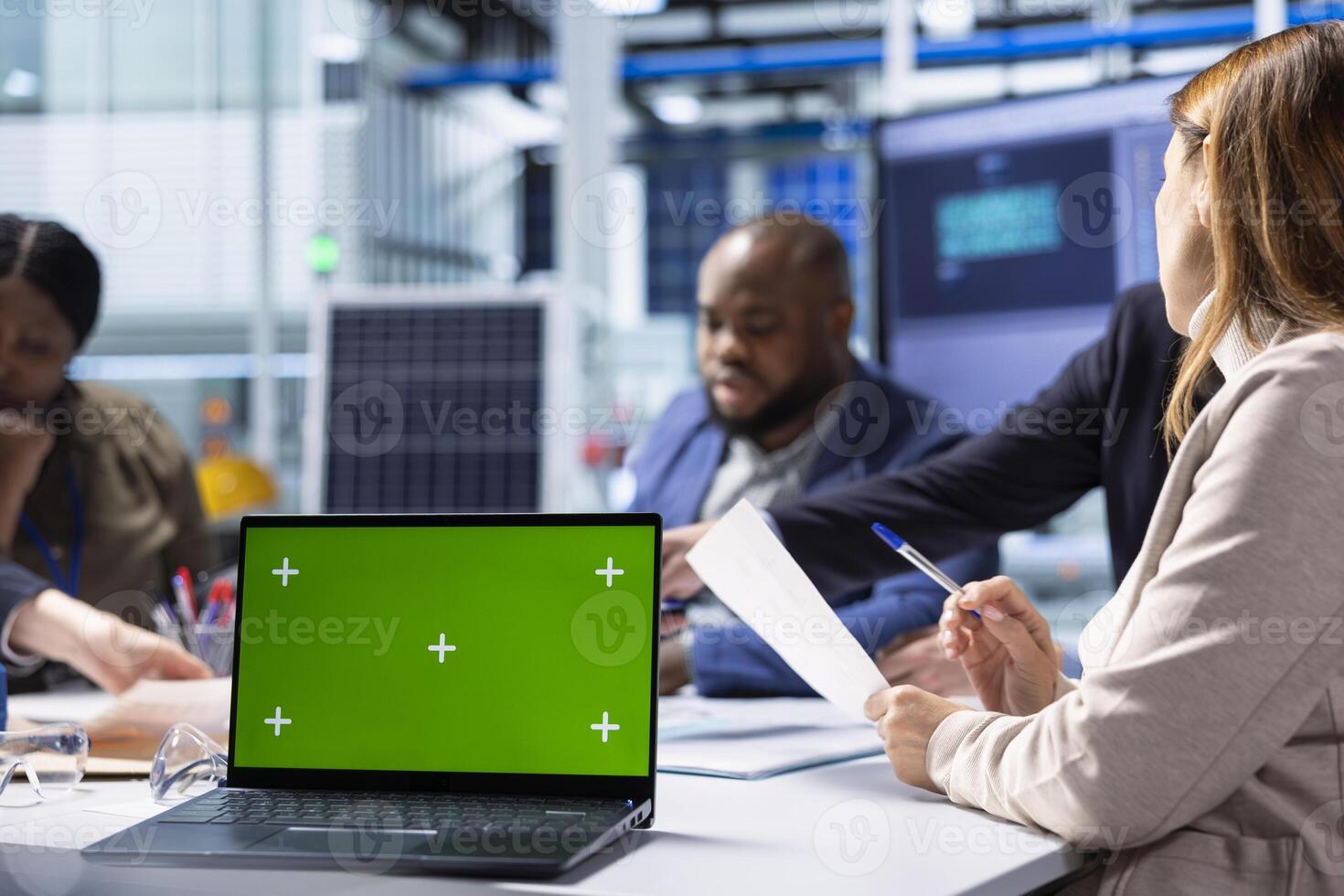 Production plant colleagues look over research and development data on mockup notebook, analyzing innovative manufacturing strategies. Businesspeople brainstorm innovations using green screen laptop photo