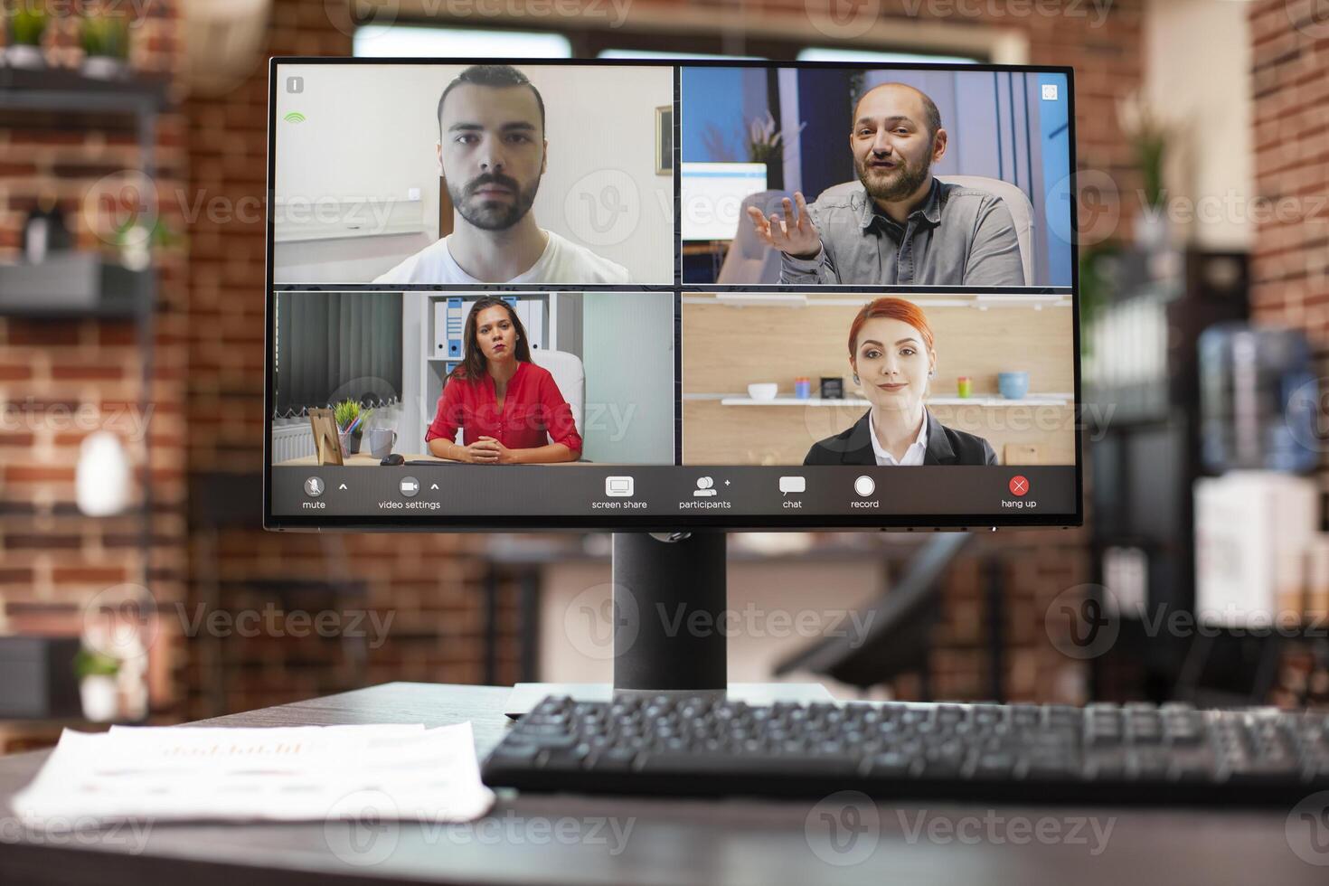 Closeup of virtual group discussion displayed on desktop pc screen in neat office setup. Computer monitor set on vacant desk shows colleagues on a videoconference, attending online training session. photo