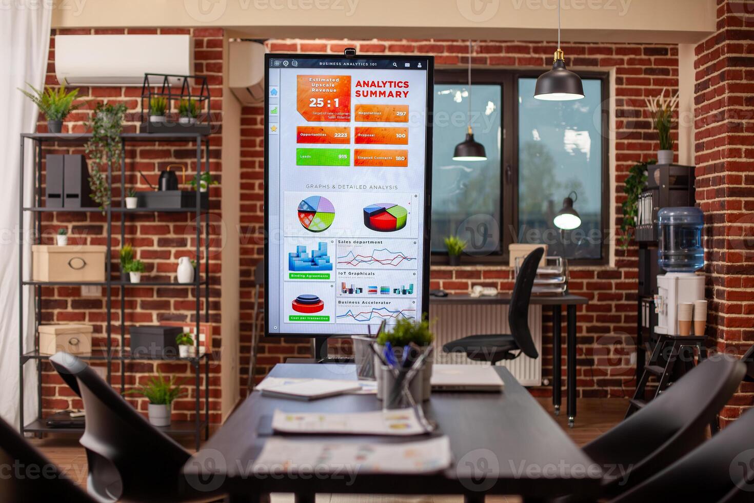 Vacant startup office with digital screen and chairs organized for company discussions. Technology and financial documents well arranged in brick wall workspace, ready for group meeting use. photo